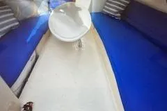 Slide: The Image of Interior of a 1996 Hunter 23.5 sailboat with blue seating and a white table. - 5
