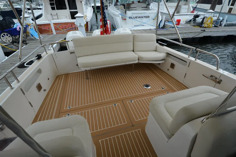 Slide: The Image of 2020 MJM 43z boat interior with cushioned seating and teak flooring at a marina. - 14