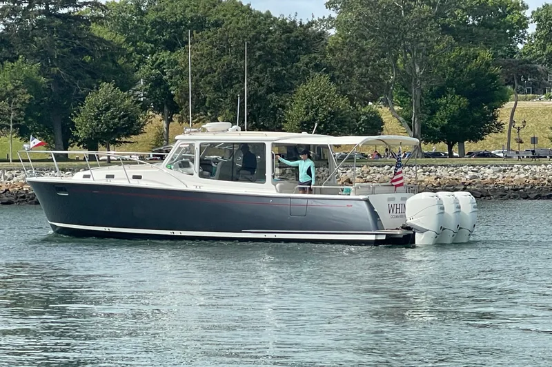 Slide: The Image of 2020 MJM 43z boat cruising on a calm waterway with lush greenery in the background. - 2