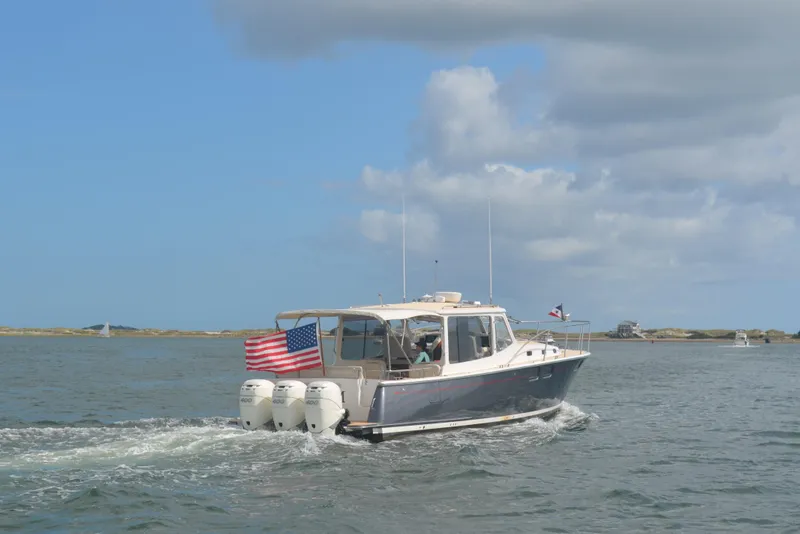 Slide: The Image of 2020 MJM 43z boat cruising on open water with American flag. - 4