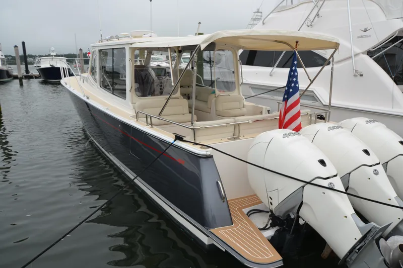 Slide: The Image of 2020 MJM 43z yacht docked, featuring triple outboard engines and American flag. - 48