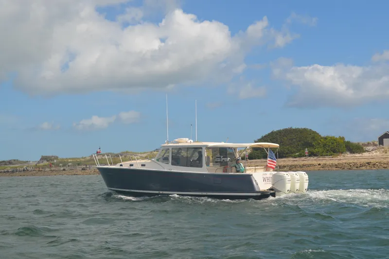 Slide: The Image of 2020 MJM 43z boat cruising on water with American flag, under blue sky. - 64
