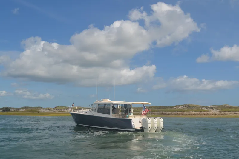 Slide: The Image of 2020 MJM 43z boat cruising on a sunny day with scenic coastal backdrop. - 67