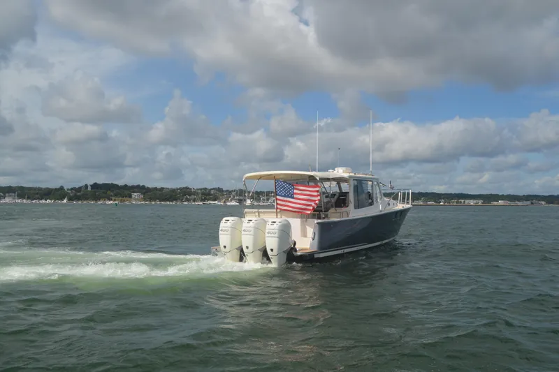 Slide: The Image of 2020 MJM 43z boat cruising on water with American flag, under cloudy sky. - 69