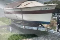 Slide: The Image of 1979 O'Day 19 sailboat on trailer, covered and parked on gravel. - 1