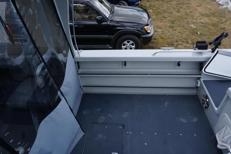 Slide: The Image of 2023 Weldcraft Ocean King 220 boat interior with seating and storage, parked near a vehicle. - 59