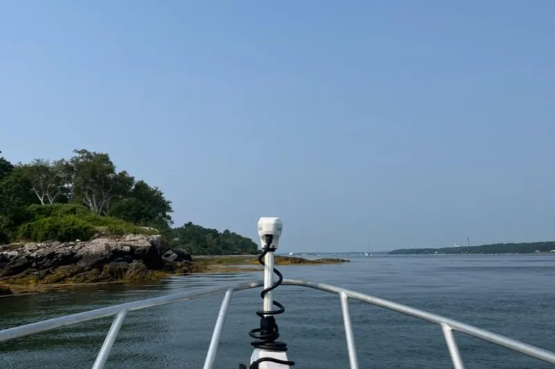 Slide: The Image of Bow view from Ocean King 220 boat, cruising near rocky shoreline, clear blue sky. - 14