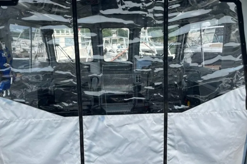Slide: The Image of 2023 Ocean King 220 boat with clear protective cover at a marina. - 2