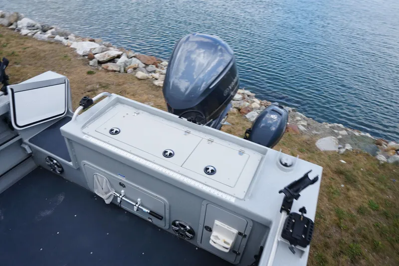 Slide: The Image of 2023 Weldcraft Ocean King 220 boat with motor, docked by rocky shoreline. - 57