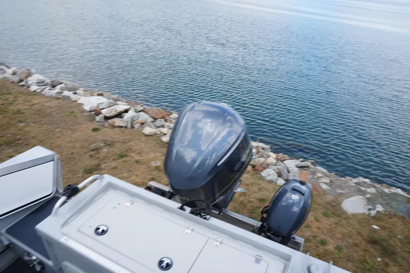 Slide: The Image of 2023 Weldcraft Ocean King 220 boat with dual outboard motors by a rocky shoreline. - 58