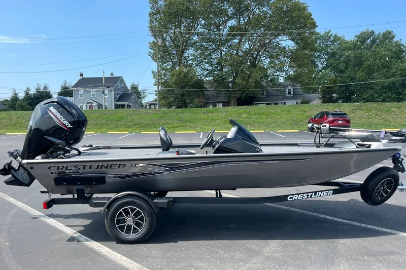 The Image of 2026 Crestliner XFC 179 boat on trailer, parked in a lot, with Mercury outboard motor. - 0