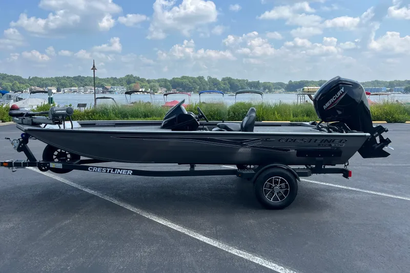 Slide: The Image of 2026 Crestliner XFC 179 fishing boat on trailer, parked near a scenic lake. - 7