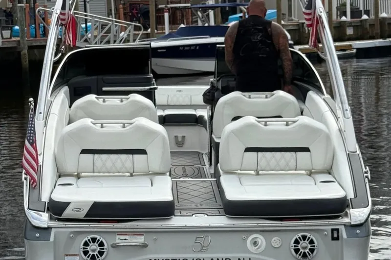 Slide: The Image of 2021 Regal LS6 boat with white seating, docked, featuring American flags. - 2