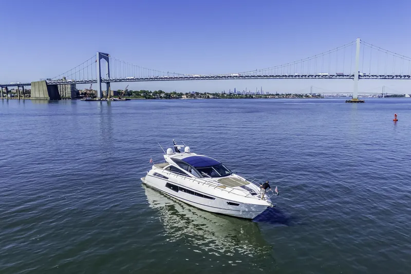 The Image of 2014 Sunseeker 68 Sport Yacht cruising near a large suspension bridge on a sunny day. - 1