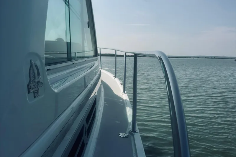 Slide: The Image of 2013 Back Cove 30 boat on calm water, side view with railing and logo. - 10