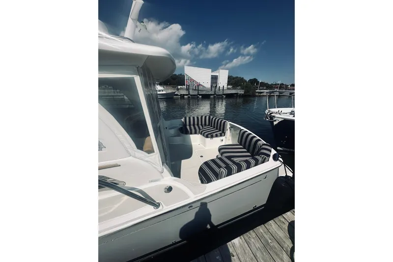 Slide: The Image of 2013 Back Cove 30 boat with striped seating docked at a marina. - 16