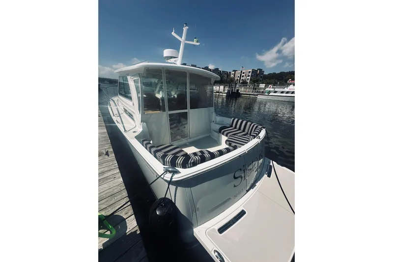 Slide: The Image of 2013 Back Cove 30 boat docked, featuring striped seating and a sleek design. - 17