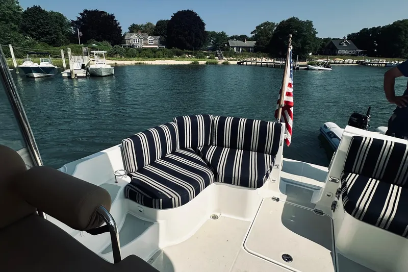 Slide: The Image of 2013 Back Cove 30 boat with striped seating, docked in a scenic marina. - 18