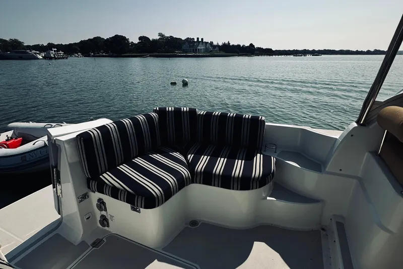 Slide: The Image of 2013 Back Cove 30 boat with striped seating, overlooking calm waters and distant shoreline. - 19