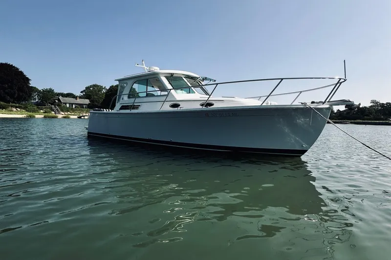 Slide: The Image of 2013 Back Cove 30 boat anchored in calm waters near a scenic shoreline. - 2