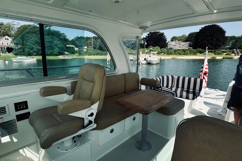 Slide: The Image of Interior of 2013 Back Cove 30 boat with seating and table, overlooking serene waterfront. - 20