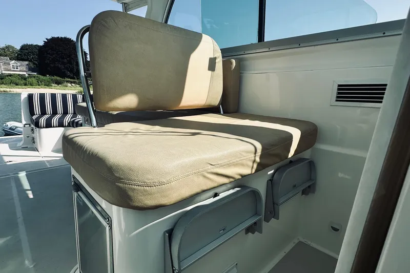 Slide: The Image of 2013 Back Cove 30 boat interior with beige cushioned seating and storage compartments. - 25
