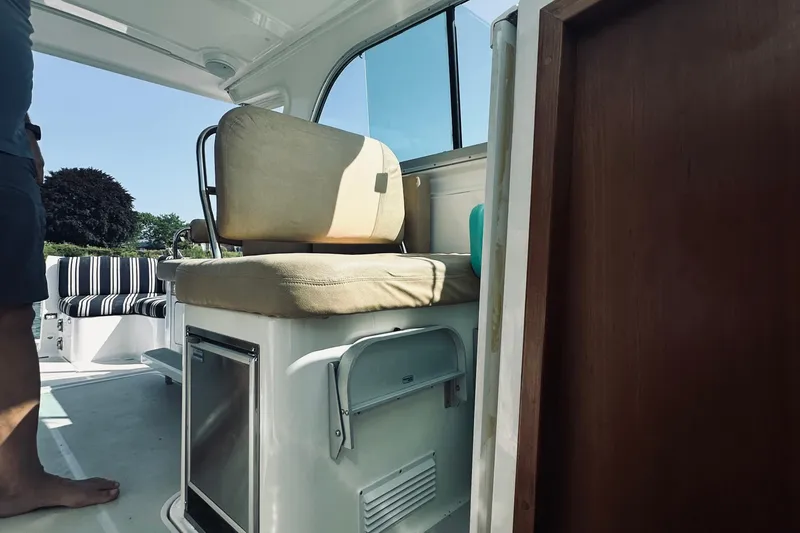 Slide: The Image of Interior of a 2013 Back Cove 30 boat, featuring seating and a compact fridge. - 26