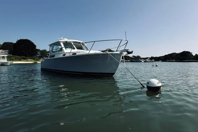 Slide: The Image of 2013 Back Cove 30 boat anchored on calm water under clear blue sky. - 3