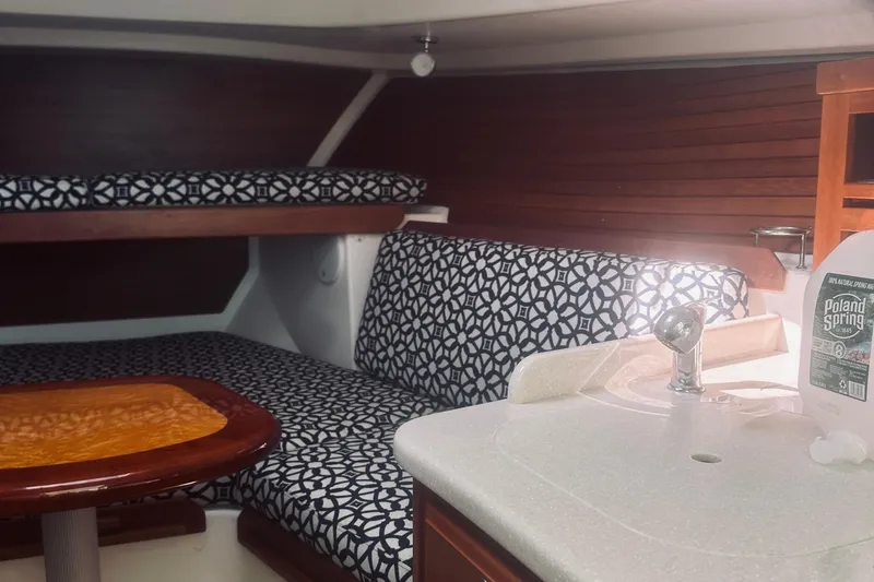 Slide: The Image of 2013 Back Cove 30 interior with patterned seating, wooden table, and compact sink area. - 49