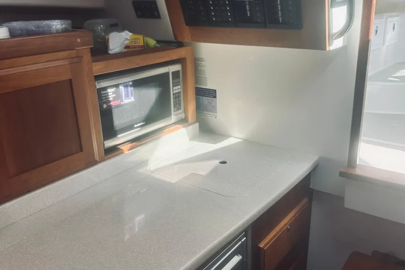 Slide: The Image of 2013 Back Cove 30 yacht interior with microwave and wooden cabinetry. - 54