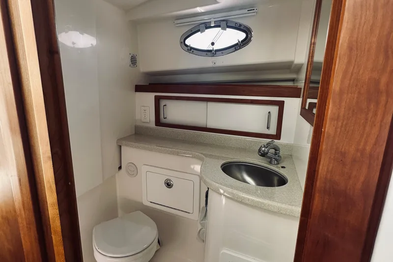 Slide: The Image of 2013 Back Cove 30 yacht bathroom with sink, toilet, and porthole window. - 58