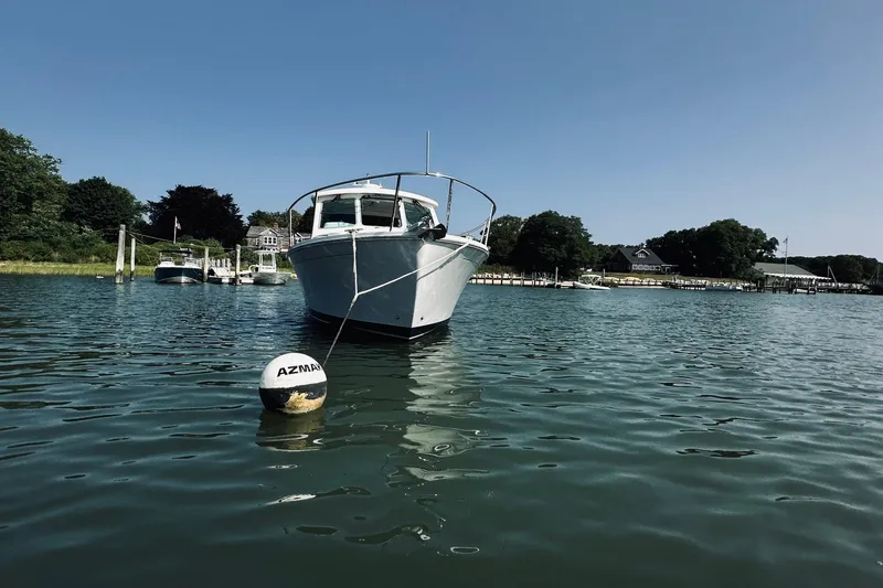 Slide: The Image of 2013 Back Cove 30 boat moored in a serene harbor with clear blue skies. - 60