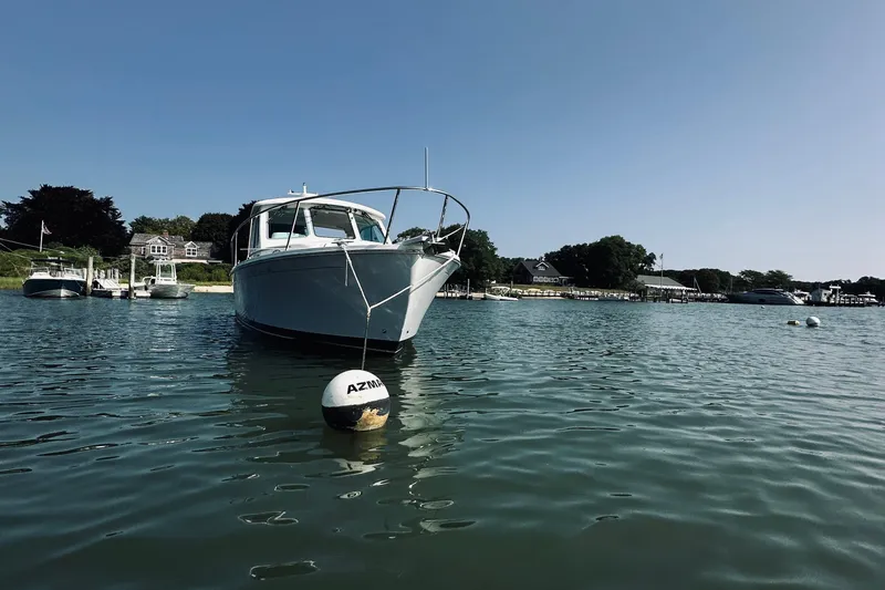 Slide: The Image of 2013 Back Cove 30 boat moored in a scenic harbor with clear blue skies. - 61