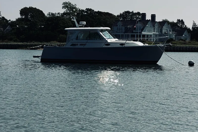 Slide: The Image of 2013 Back Cove 30 boat anchored on calm water near elegant waterfront homes. - 7