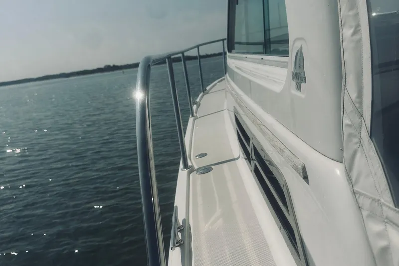 Slide: The Image of 2013 Back Cove 30 boat on calm water, showcasing sleek design and railing. - 9