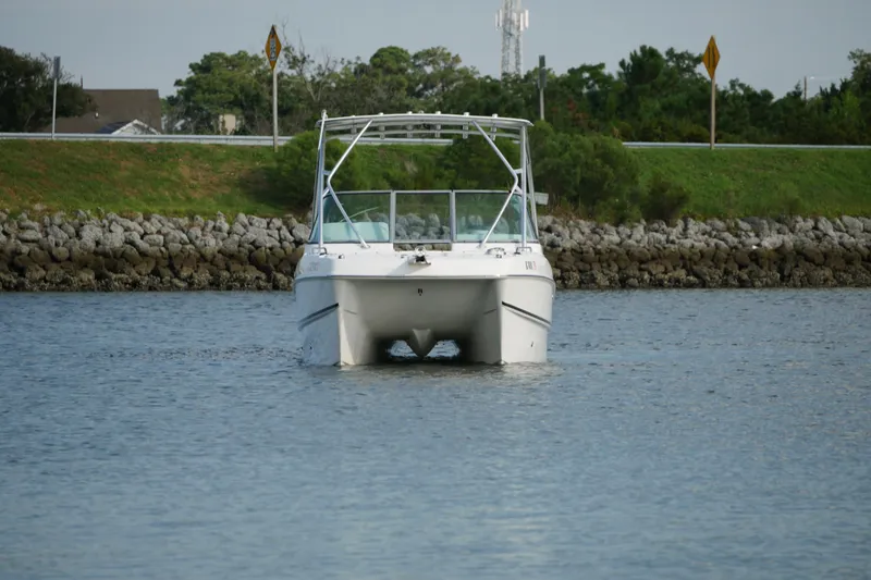Slide: The Image of 2014 Carolina Cat 23DC boat cruising on a calm waterway, surrounded by greenery. - 14