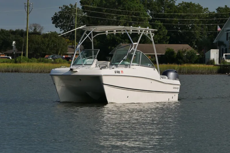 Slide: The Image of 2014 Carolina Cat 23DC boat on calm water, surrounded by greenery and houses. - 15