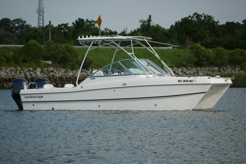 Slide: The Image of 2014 Carolina Cat 23DC boat on water, featuring dual engines and sleek design. - 2