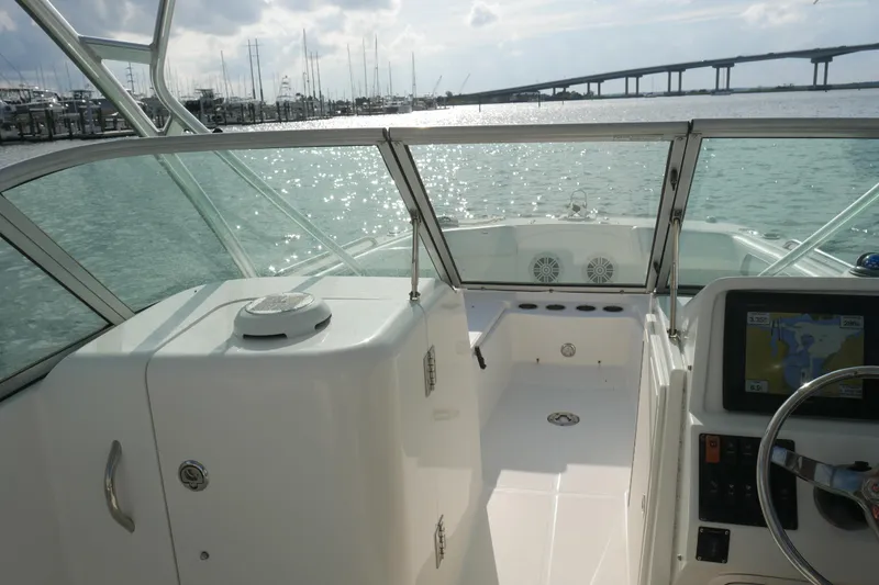 Slide: The Image of 2014 Carolina Cat 23DC boat interior with steering wheel and navigation system, overlooking marina. - 24