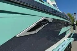 Slide: The Image of 2021 Centurion Ri245 boat on trailer, mint green and black, parked outdoors. - 2