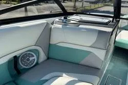 Slide: The Image of 2021 Centurion Ri245 boat interior with teal and gray seating, speaker, and cup holders. - 8