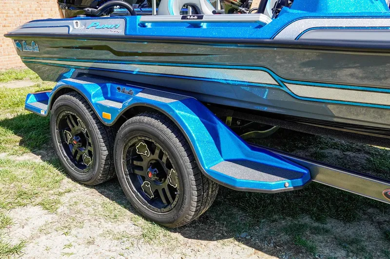 Slide: The Image of 2025 Bass Cat Puma STS boat trailer with blue accents and black wheels. - 24