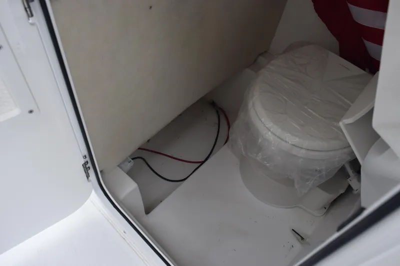 Slide: The Image of Interior of 2025 Sea Hunt Ultra 245 SE boat featuring a compact marine toilet. - 14