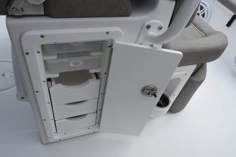Slide: The Image of 2025 Sea Hunt Ultra 245 SE boat storage compartment with open door and drawers. - 18