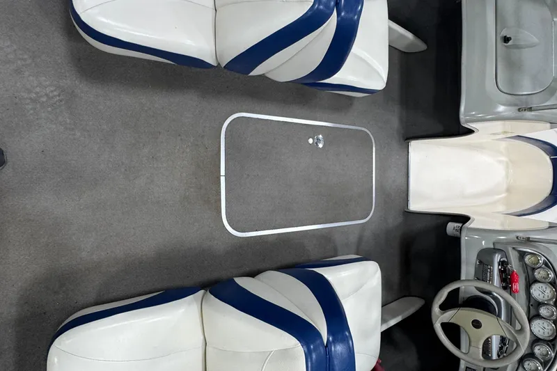 Slide: The Image of 2005 Bayliner 205 BR boat interior with white and blue seating, steering wheel, and dashboard. - 12
