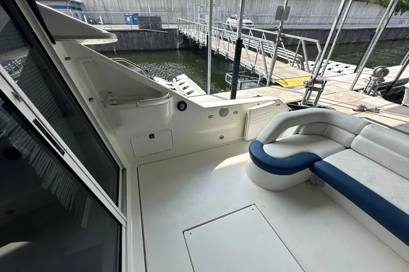 Slide: The Image of 1995 Sea Ray 440 Express Bridge interior with white seating, docked at marina. - 14