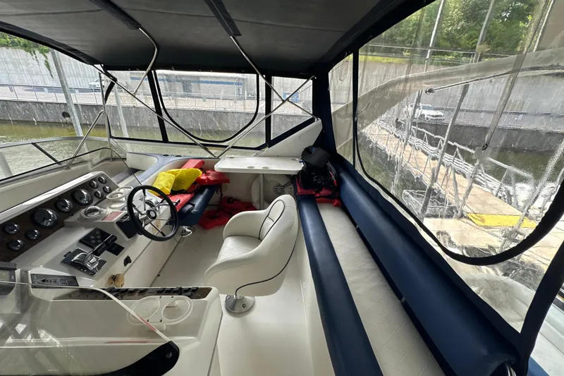 Slide: The Image of 1995 Sea Ray 440 Express Bridge cockpit with steering wheel, seating, and clear canopy. - 19