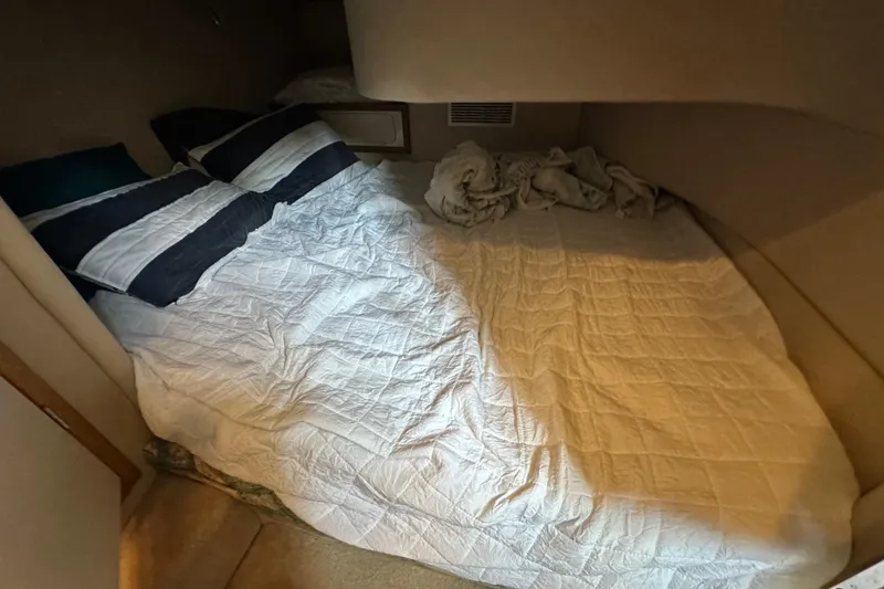Slide: The Image of Cozy cabin bed inside 1995 Sea Ray 440 Express Bridge yacht, featuring striped pillows and white bedding. - 38