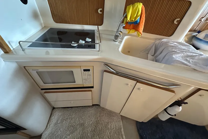 Slide: The Image of 1995 Sea Ray 440 Express Bridge kitchen with stove, microwave, and sink. - 48
