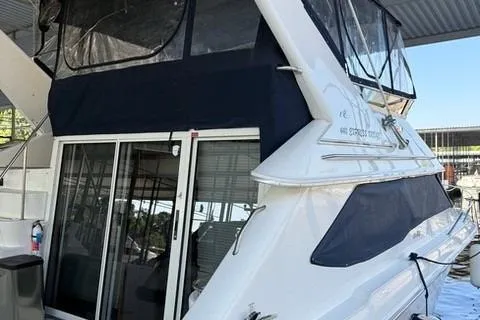 Slide: The Image of 1995 Sea Ray 440 Express Bridge yacht docked, featuring sleek design and covered upper deck. - 6